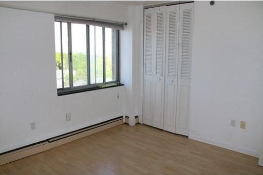 unfurnished bedroom featuring a baseboard heating unit, light hardwood / wood-style flooring, and a closet