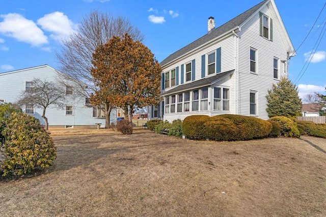 view of side of property featuring a shingled roof, fence, and a chimney