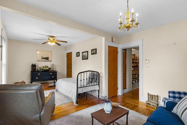 living area featuring light wood-type flooring, baseboard heating, and ceiling fan with notable chandelier