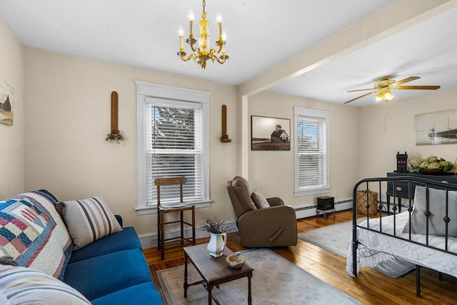 living area featuring baseboard heating, ceiling fan with notable chandelier, baseboards, and wood finished floors