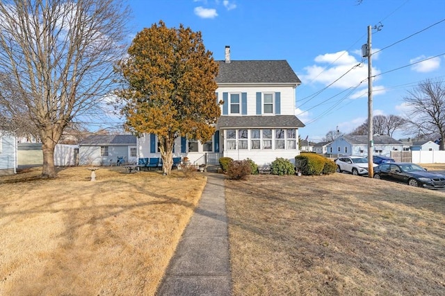 view of front of home with a front yard, fence, a sunroom, a chimney, and a shingled roof