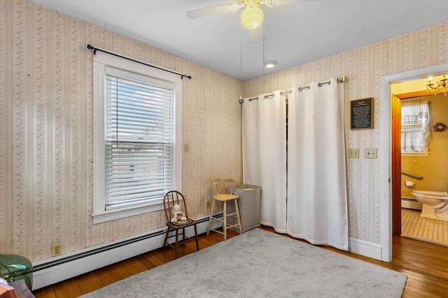 interior space with a baseboard radiator, hardwood / wood-style flooring, ceiling fan, and wallpapered walls