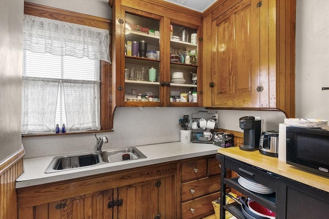 kitchen with brown cabinets, light countertops, black microwave, and a sink