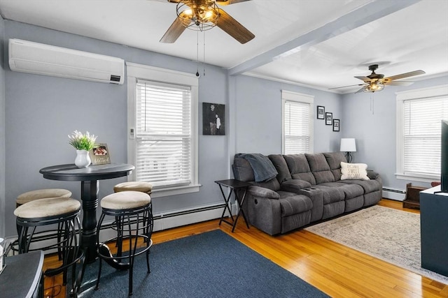 living area featuring plenty of natural light, wood finished floors, a ceiling fan, and a wall unit AC