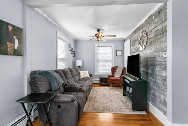 living room with an accent wall, crown molding, wood finished floors, and baseboard heating