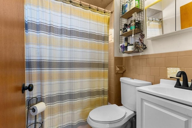 full bath featuring vanity, a wainscoted wall, curtained shower, tile walls, and toilet