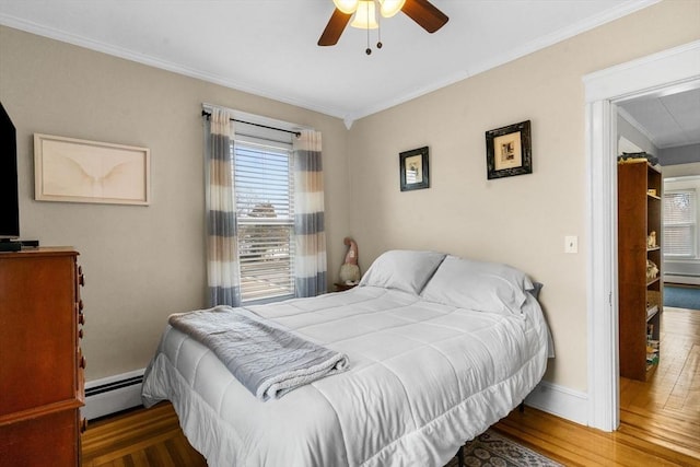 bedroom featuring ornamental molding, a ceiling fan, a baseboard heating unit, wood finished floors, and baseboards