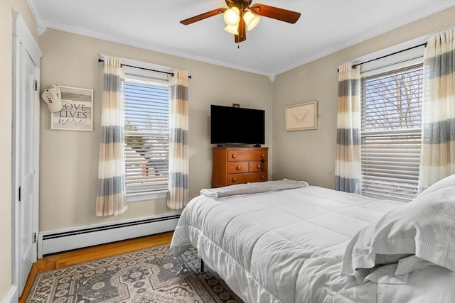 bedroom with baseboard heating, wood finished floors, a ceiling fan, and ornamental molding