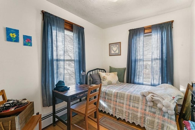 bedroom with a baseboard radiator, a textured ceiling, and wood finished floors