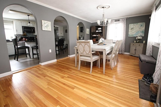 dining room featuring crown molding, a notable chandelier, and light hardwood / wood-style flooring