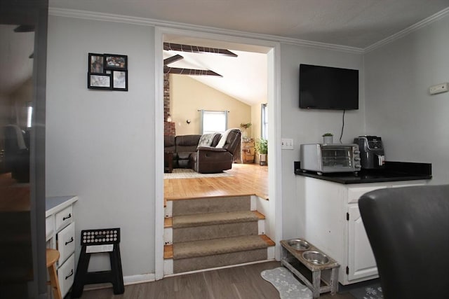 stairway featuring lofted ceiling, hardwood / wood-style flooring, and ornamental molding