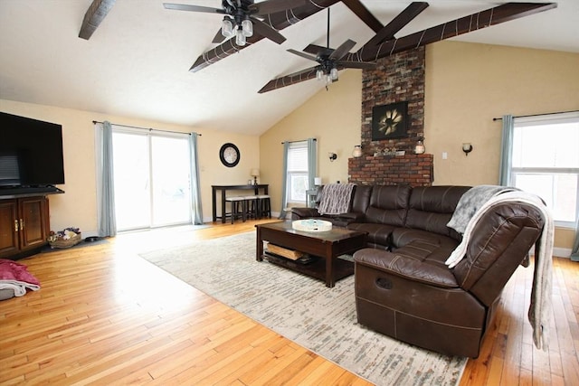 living room with beam ceiling, plenty of natural light, and light wood-type flooring