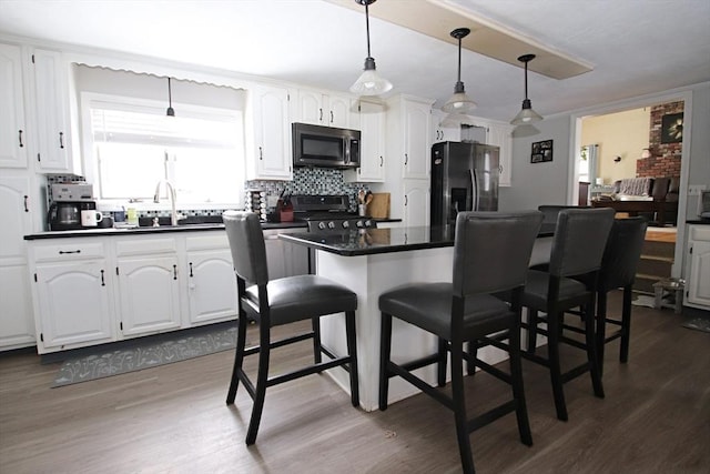 kitchen with sink, a breakfast bar area, white cabinetry, pendant lighting, and stainless steel appliances