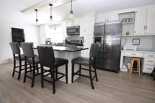 kitchen featuring a kitchen bar, decorative light fixtures, white cabinets, and appliances with stainless steel finishes