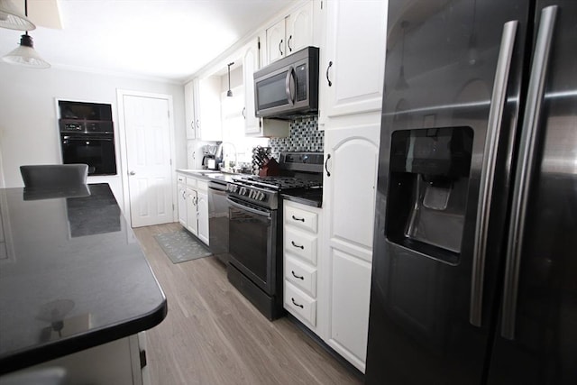 kitchen featuring sink, white cabinetry, light hardwood / wood-style floors, decorative backsplash, and black appliances