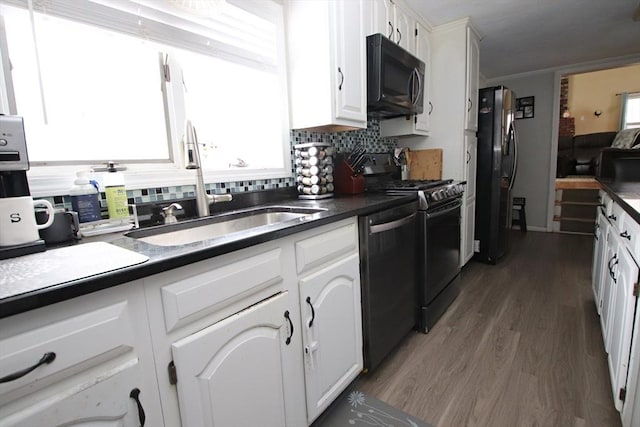 kitchen featuring sink, dishwashing machine, white cabinets, stainless steel fridge with ice dispenser, and black electric range