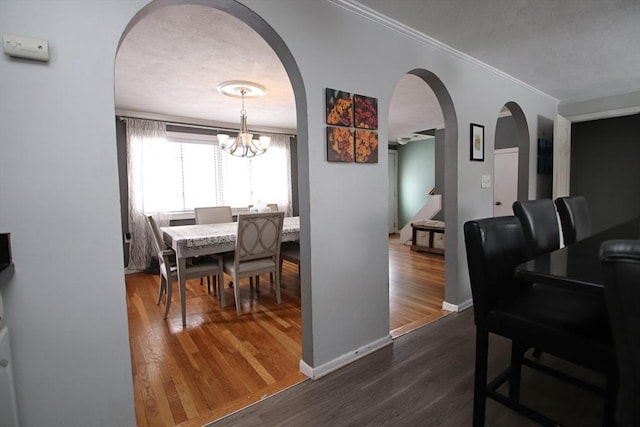 dining space featuring an inviting chandelier, crown molding, and dark wood-type flooring