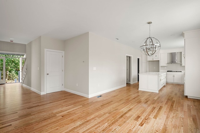 unfurnished living room featuring a chandelier and light wood-type flooring