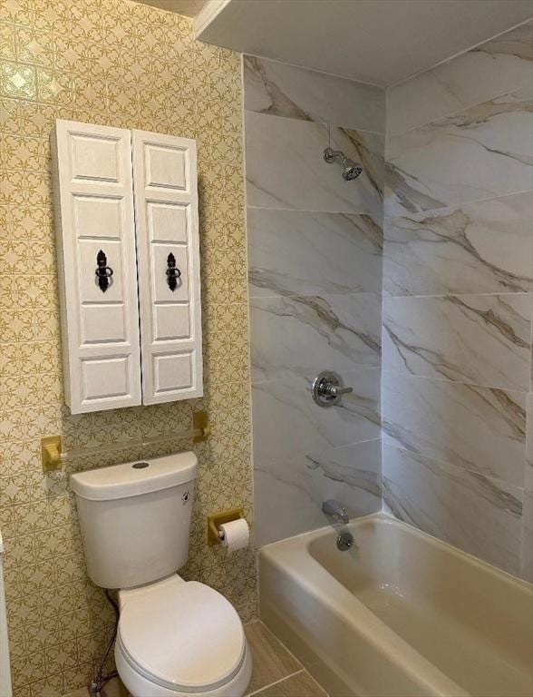 bathroom with toilet, wallpapered walls, and bathtub / shower combination