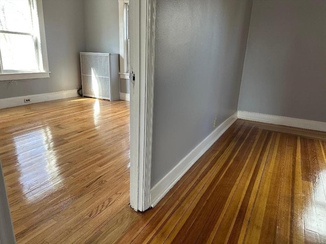 spare room with baseboards and wood finished floors