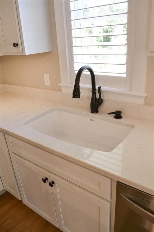 interior details featuring light stone countertops, hardwood / wood-style flooring, white cabinetry, and sink