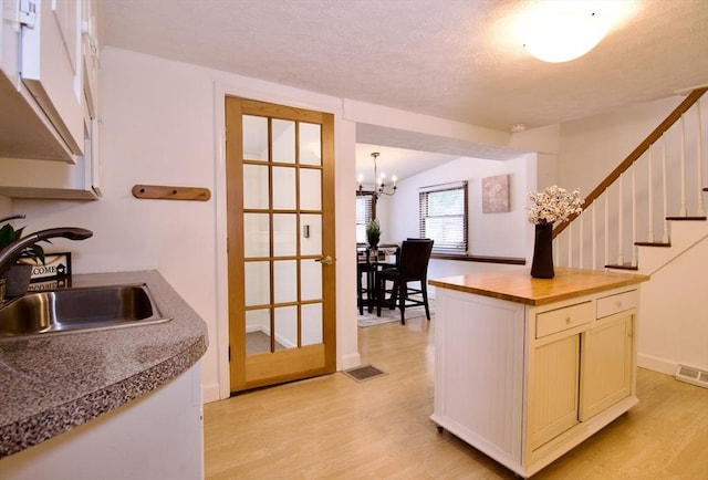 kitchen featuring a chandelier, light wood-style flooring, a sink, and visible vents