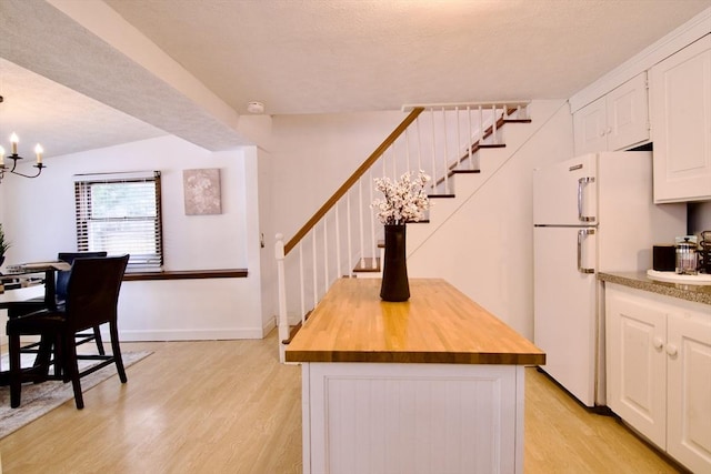 kitchen featuring freestanding refrigerator, white cabinets, a kitchen island, and light wood-style flooring