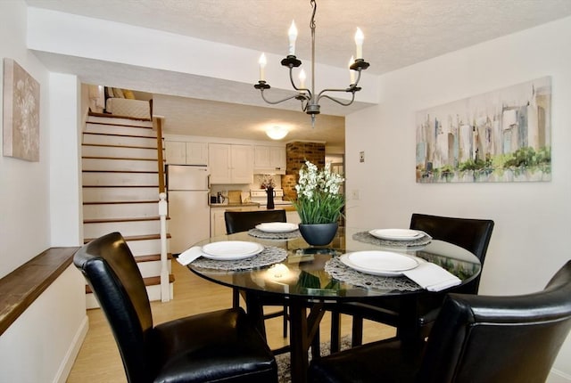 dining area featuring stairs, light wood finished floors, a textured ceiling, and an inviting chandelier