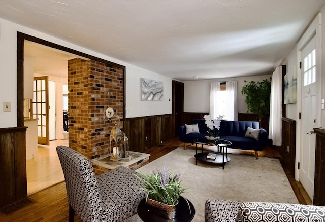 living area with wainscoting, wood finished floors, and wooden walls