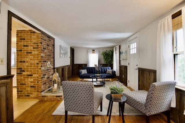 living area featuring wood walls, wood finished floors, and wainscoting