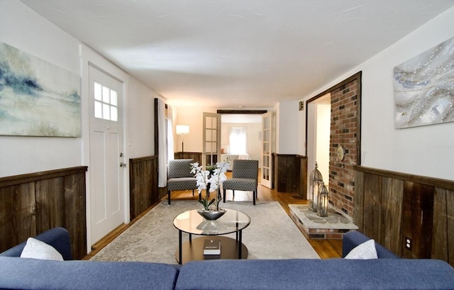 living area with a wainscoted wall, wooden walls, plenty of natural light, and light wood-style floors