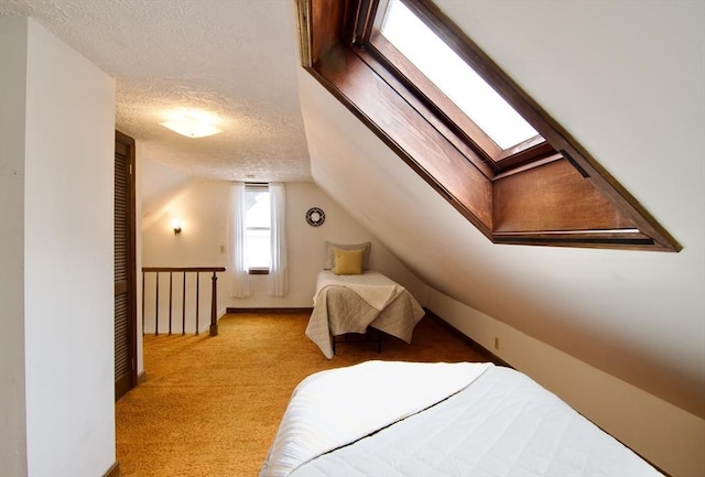 bedroom featuring vaulted ceiling with skylight, light carpet, and a textured ceiling