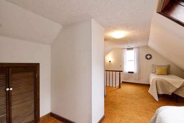 unfurnished bedroom featuring light carpet, a textured ceiling, lofted ceiling, and baseboards