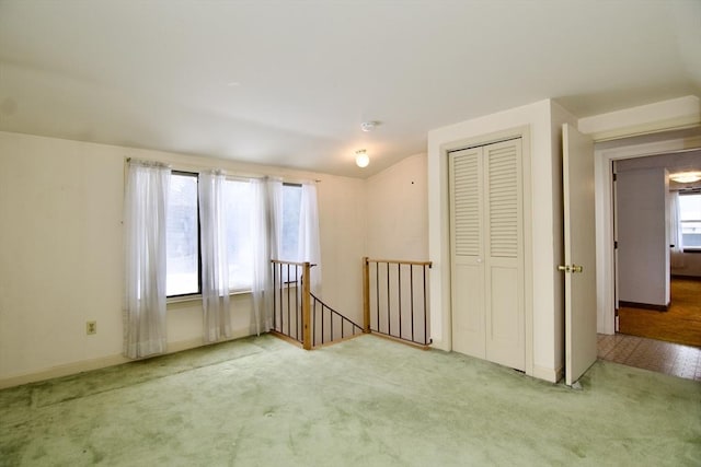 carpeted empty room with lofted ceiling and baseboards