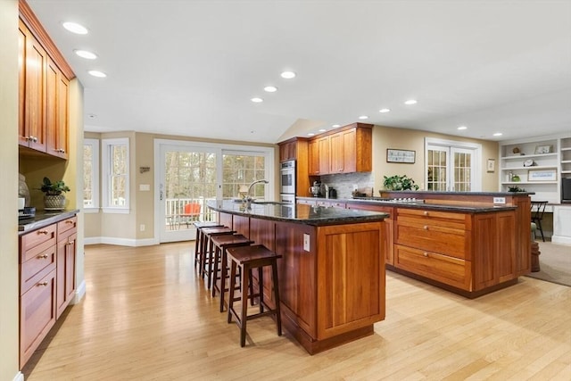 kitchen featuring a breakfast bar area, light wood-style flooring, a kitchen island with sink, and a sink