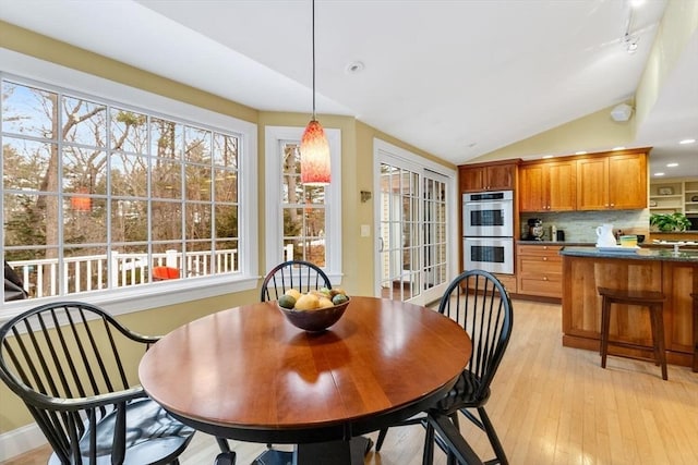 dining space featuring light wood-type flooring and lofted ceiling