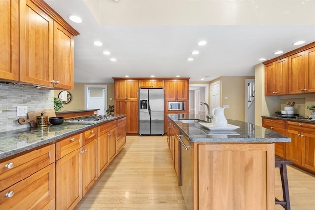 kitchen with a sink, appliances with stainless steel finishes, recessed lighting, and light wood finished floors