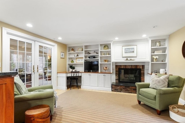 living area featuring recessed lighting, french doors, baseboards, a brick fireplace, and built in study area