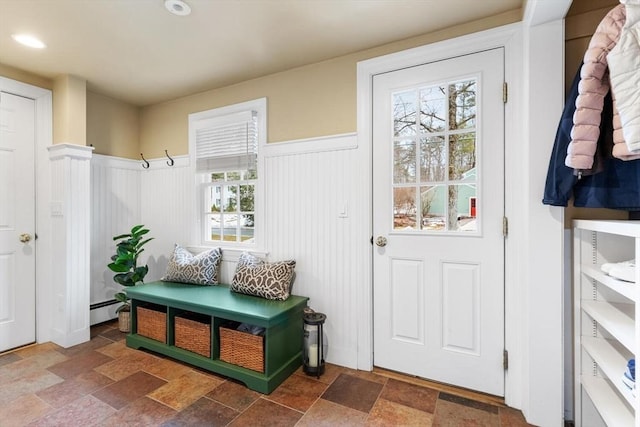 mudroom featuring plenty of natural light, stone finish floor, a wainscoted wall, and a baseboard radiator