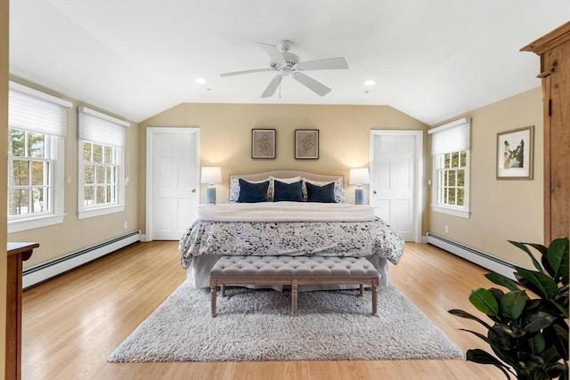 bedroom featuring a baseboard heating unit, lofted ceiling, and light wood-style floors