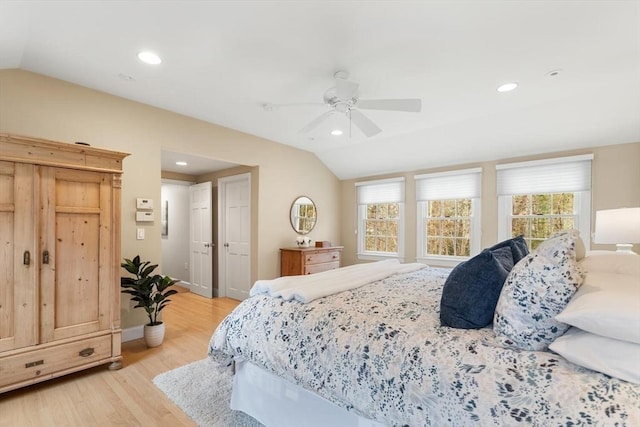 bedroom with vaulted ceiling, multiple windows, and light wood-type flooring