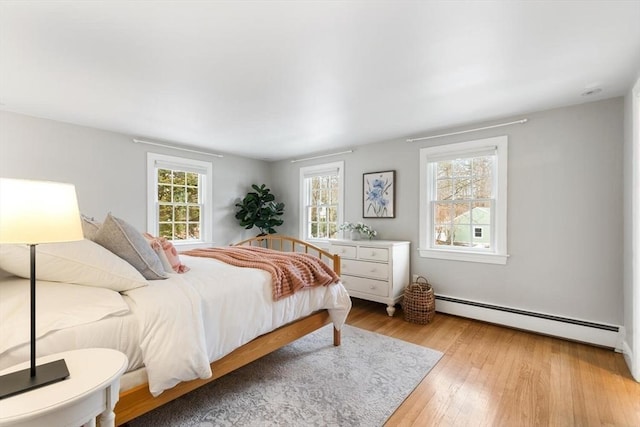 bedroom with baseboard heating and light wood finished floors