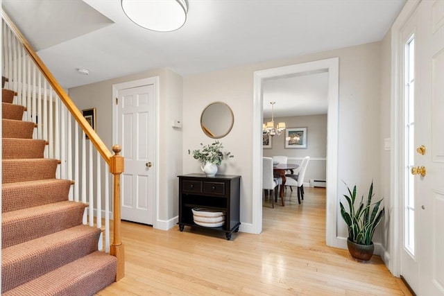 entryway featuring stairway, baseboards, an inviting chandelier, light wood-style floors, and baseboard heating