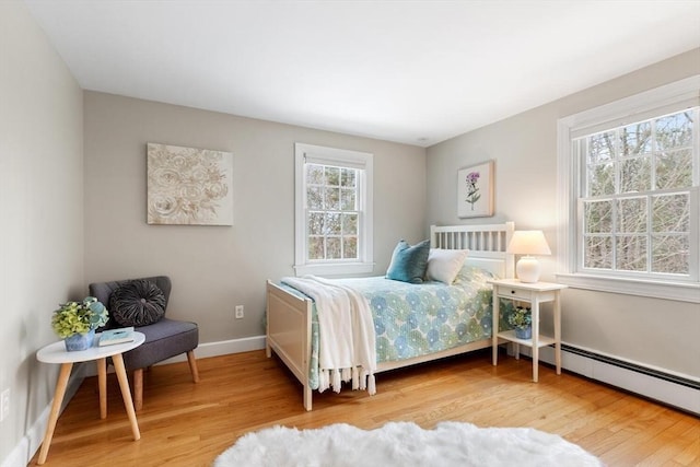 bedroom with a baseboard heating unit, baseboards, and wood finished floors