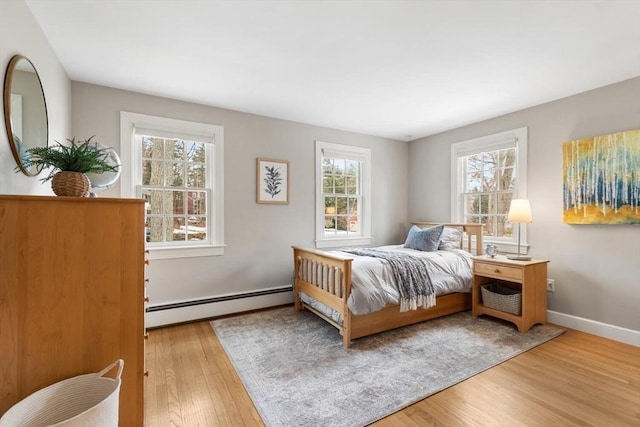 bedroom with baseboards, baseboard heating, and wood finished floors