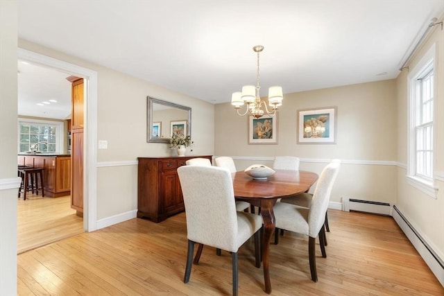 dining space featuring a baseboard radiator, plenty of natural light, and light wood-style flooring