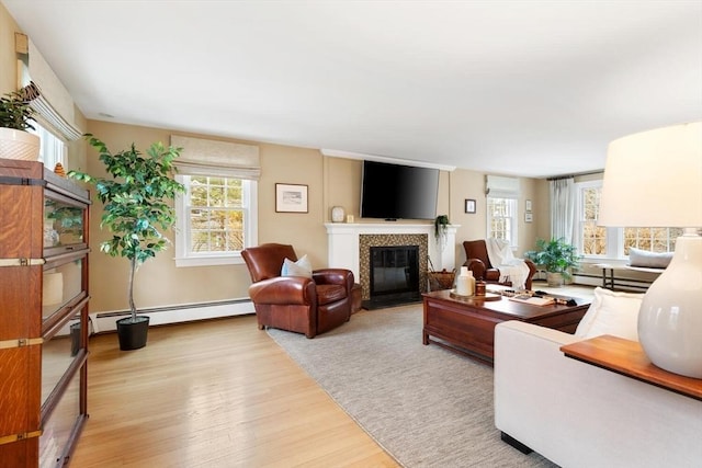 living room with a glass covered fireplace, light wood finished floors, and baseboard heating