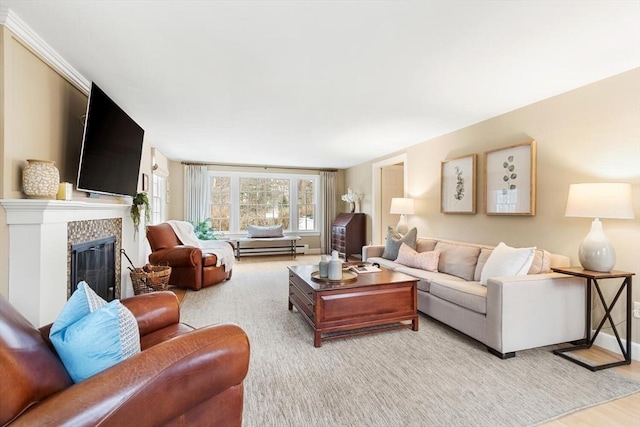 living area featuring a glass covered fireplace, baseboards, baseboard heating, and light wood-type flooring