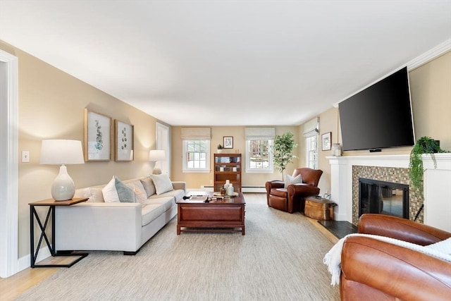 living area featuring a tiled fireplace, baseboards, light wood-type flooring, and a baseboard radiator