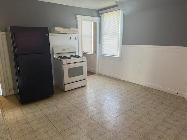 kitchen featuring white gas range oven and black fridge